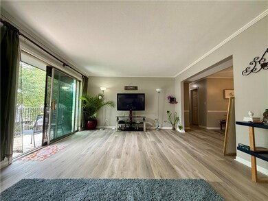 Living area featuring wood finished floors, baseboards, and crown molding