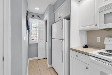 Kitchen featuring light tile patterned flooring, white appliances, white cabinetry, baseboards, and light countertops