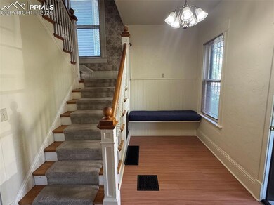Staircase featuring healthy amount of natural light, a wainscoted wall, wood finished floors, and a chandelier