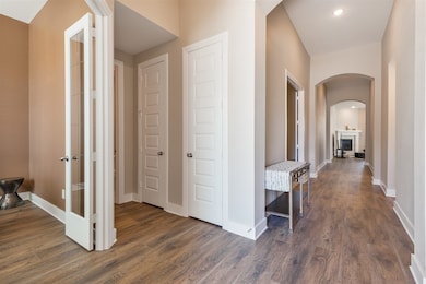 Hallway featuring arched walkways, dark wood-style floors, and recessed lighting