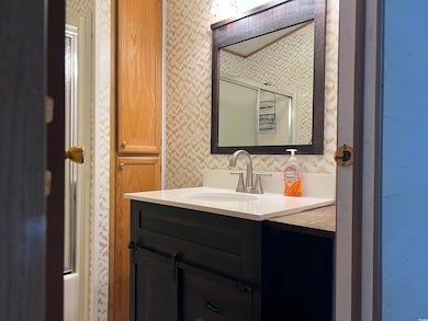 Bathroom featuring a shower with shower door, wall