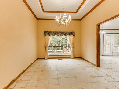 Empty room with an inviting chandelier, ornamental molding, a raised ceiling, and light tile floors