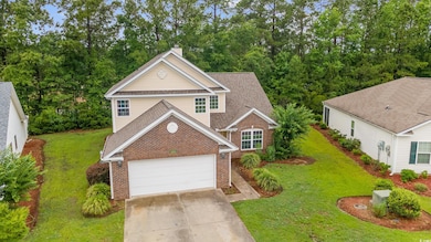 Traditional-style home with brick siding, a chimney, concrete driveway, and a front yard