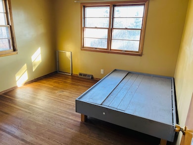 Bedroom with hardwood flooring and baseboards