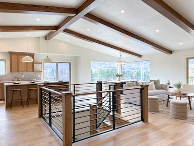 Great Room with vaulted ceilings, hardwood floors, custom railing, and custom kitchen.