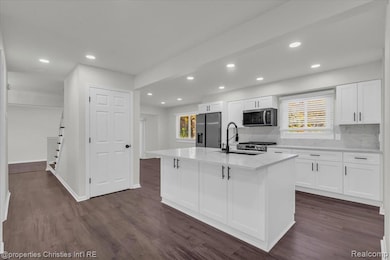 Kitchen featuring white cabinets, dark wood-style floors, recessed lighting, stainless steel appliances, and tasteful backsplash