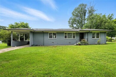 View of front facade with concrete driveway, a carport, a front lawn, crawl space, and brick siding