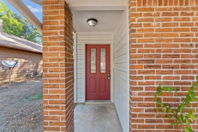 Entrance to property featuring brick siding and covered porch