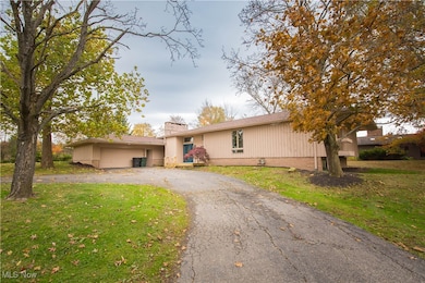 Ranch-style home with a front yard, a garage, a chimney, and asphalt driveway