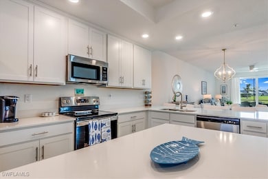 Kitchen featuring white cabinetry, sink, stainless steel appliances, a chandelier, and pendant lighting