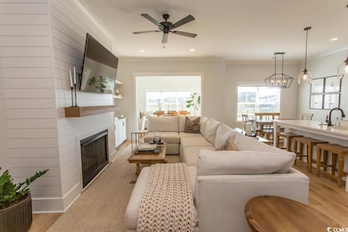 Living area featuring crown molding, a fireplace, light wood finished floors, a ceiling fan, and recessed lighting