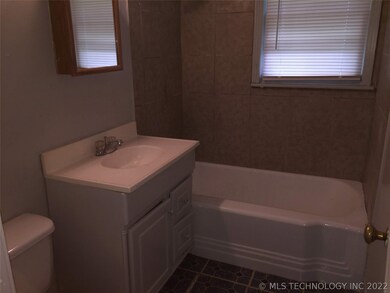 Hall bathroom with tile surround above tub.