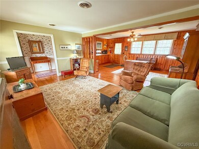 Living area with visible vents, ceiling fan, crown