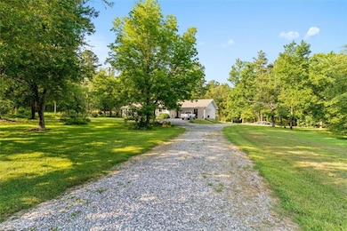 Obstructed view of property with a front yard and gravel driveway