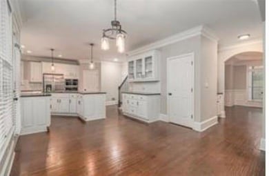 Kitchen featuring arched walkways, white cabinetry