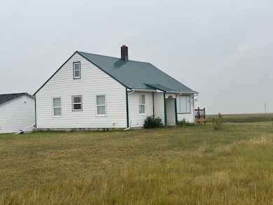 Rear view of house featuring a metal roof, a chimney, and a yard