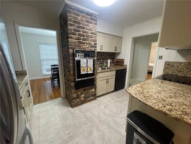 Kitchen featuring black appliances, light stone counters, tasteful backsplash, a sink, and a warming drawer