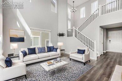 Living area with stairs, baseboards, an inviting chandelier, wood finished floors, and a high ceiling, VIRTUALLY STAGED