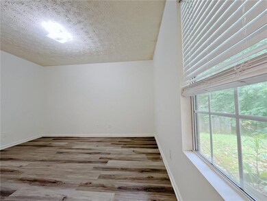 Unfurnished bedroom with wood finished floors, baseboards, and a textured ceiling