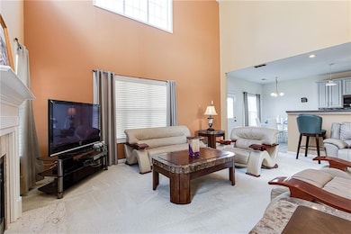 Carpeted living room with a towering ceiling, plenty of natural light, and a notable chandelier