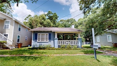 View of front of home featuring a front lawn, a porch, a chimney, and roof with shingles