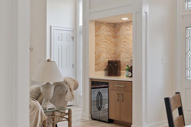 Bar area featuring beverage cooler, light wood-style flooring, and baseboards