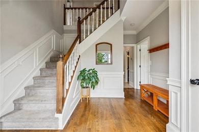 Stairs featuring a decorative wall, wainscoting, wood finished floors, and ornamental molding