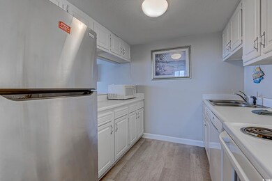 Kitchen with white appliances, a sink, light wood-