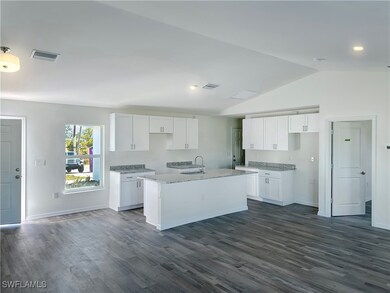 Kitchen with lofted ceiling, a sink, a center isla