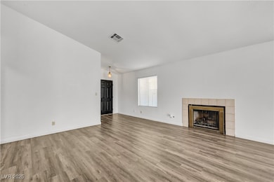 Unfurnished living room featuring light wood-style floors and a tiled fireplace