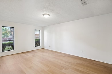 Empty room featuring light wood-style floors and a textured ceiling