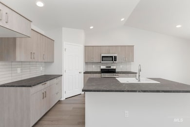 Kitchen featuring appliances with stainless steel finishes, light wood-type flooring, backsplash, light brown cabinets, and recessed lighting