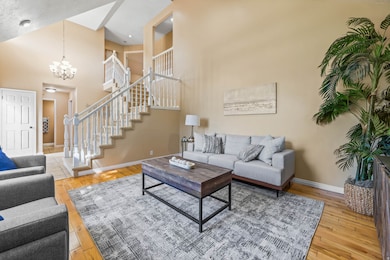Living room featuring a high ceiling, stairway, light wood-style floors, and a chandelier