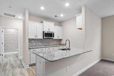 Kitchen featuring white cabinets, light stone coun