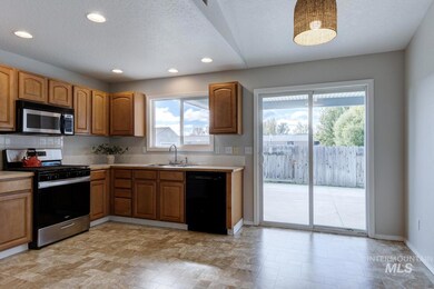 Kitchen featuring stainless steel appliances, light countertops, backsplash, a textured ceiling, and brown cabinets