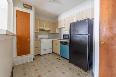 Kitchen featuring freestanding refrigerator, dishwashing machine, white stove, under cabinet range hood, and cream cabinets