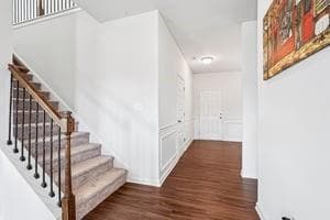 Hall with finished floors, stairway, and baseboards