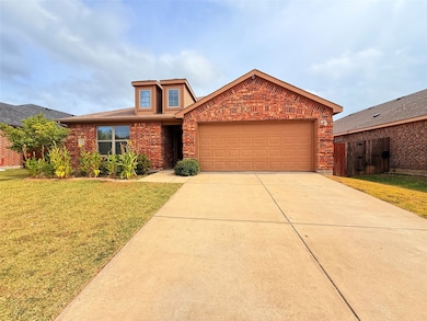 View of front of house featuring a front lawn, brick siding, driveway, and an attached garage