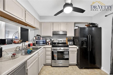 Kitchen with light countertops, stainless steel appliances, backsplash, ceiling fan, and under cabinet range hood