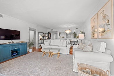 Living area featuring crown molding, a chandelier, and wood finished floors