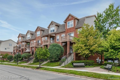 View of front of property with brick siding, a residential view, stairs, and a balcony