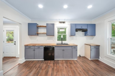 Kitchen featuring wood counters, black dishwasher,