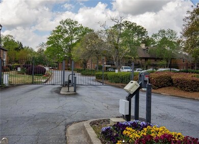 View of asphalt road with a gate, curbs, and a gated entry