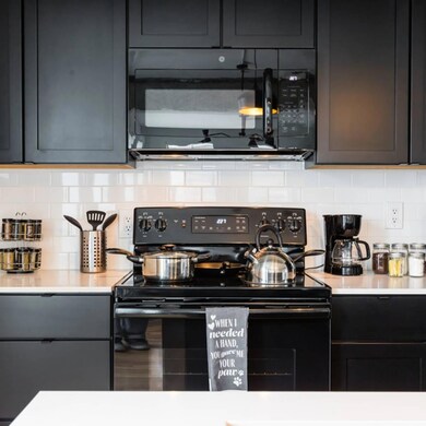Kitchen with black appliances and tasteful backspl