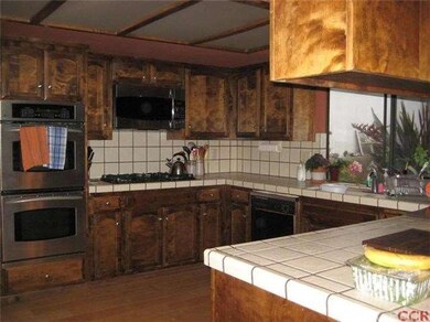 KItchen with wood flooring, tiled counters and sta