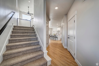 Stairway with wood finished floors, a textured ceiling, recessed lighting, and ceiling fan