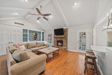 Living room featuring a ceiling fan, a fireplace, light wood finished floors, and built in shelves