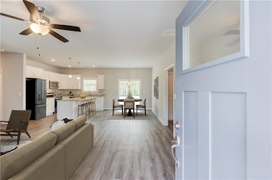 Living area with light wood finished floors, a ceiling fan, recessed lighting, and baseboards