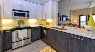 Kitchen featuring white cabinetry, light hardwood / wood-style flooring, backsplash, stainless steel appliances, and sink