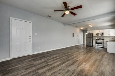 Unfurnished living room with dark wood finished floors, ceiling fan, a textured ceiling, and beamed ceiling